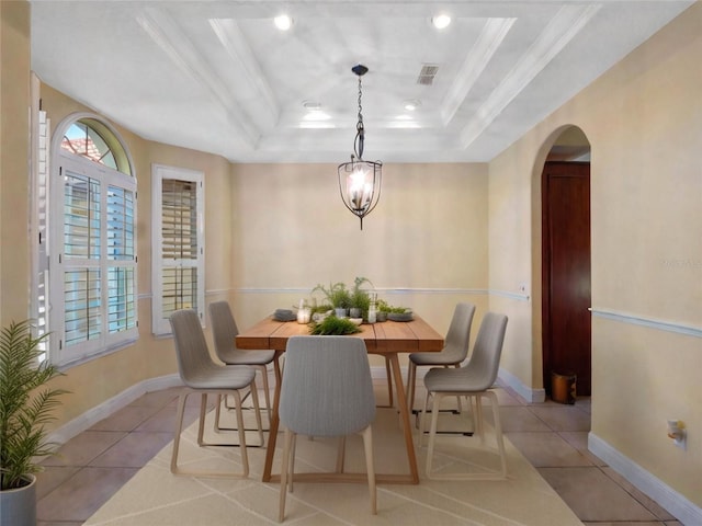 tiled dining area featuring a raised ceiling and ornamental molding