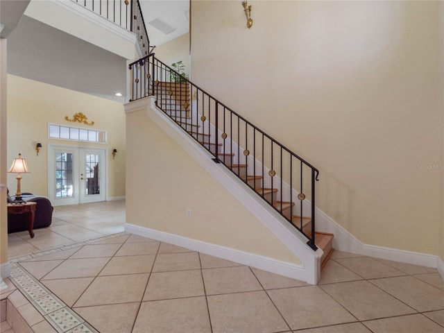 stairs with tile patterned flooring, a high ceiling, and french doors