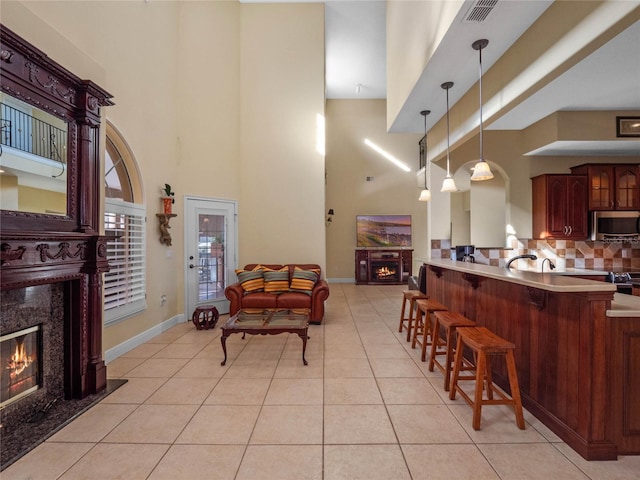 kitchen featuring a premium fireplace, hanging light fixtures, appliances with stainless steel finishes, and a towering ceiling