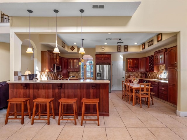 kitchen featuring backsplash, a breakfast bar, kitchen peninsula, and stainless steel appliances