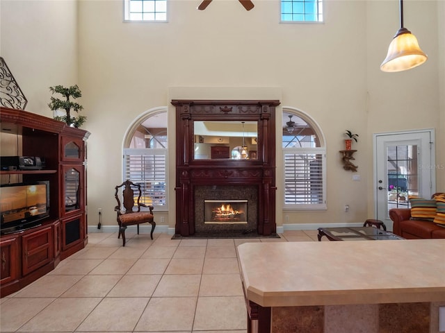 living room featuring a wealth of natural light, light tile patterned floors, a fireplace, and a high ceiling