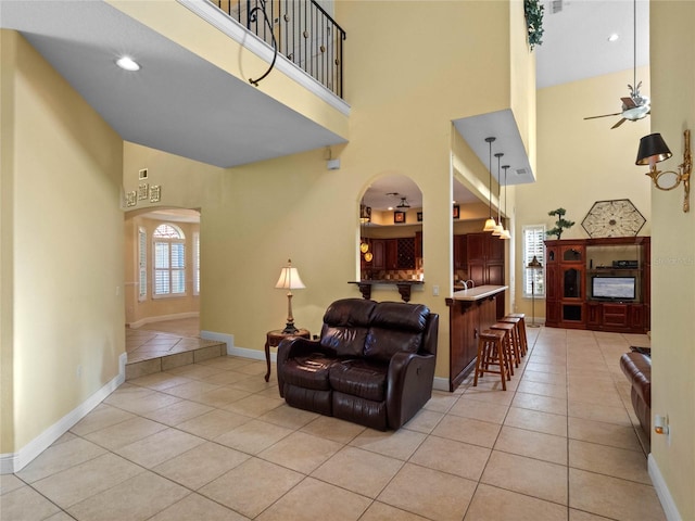 tiled living room with a towering ceiling and ceiling fan