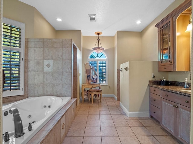 bathroom with a wealth of natural light, tile patterned flooring, vanity, and a relaxing tiled tub