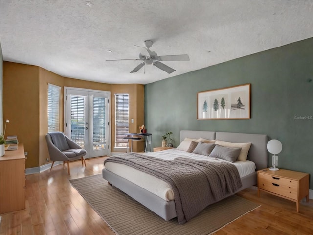 bedroom featuring french doors, hardwood / wood-style flooring, ceiling fan, access to exterior, and a textured ceiling