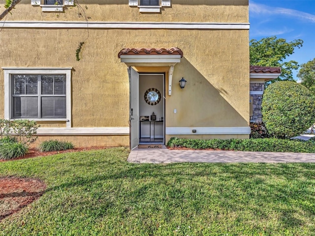 view of exterior entry featuring a yard