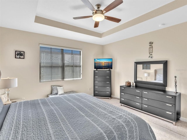 carpeted bedroom with ceiling fan and a raised ceiling