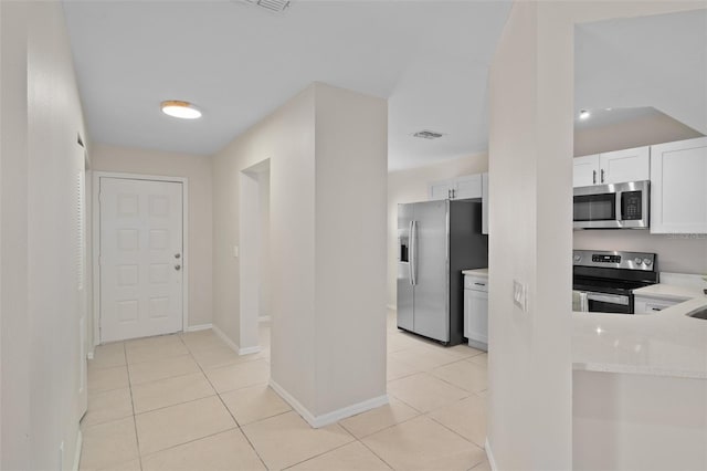 interior space with white cabinets, light tile patterned flooring, and appliances with stainless steel finishes