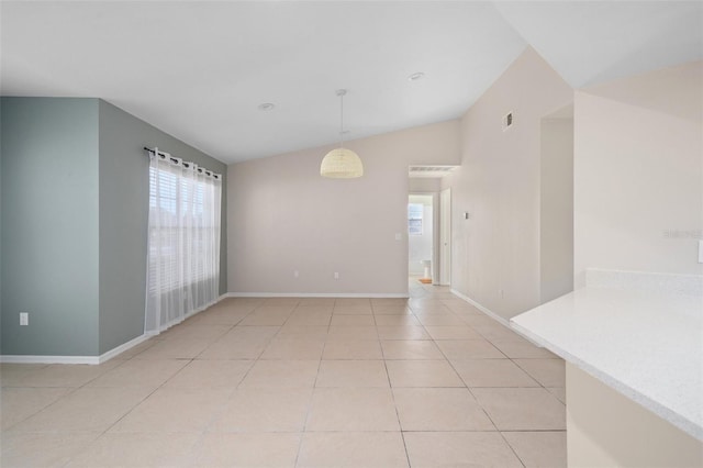 spare room featuring lofted ceiling and light tile patterned flooring