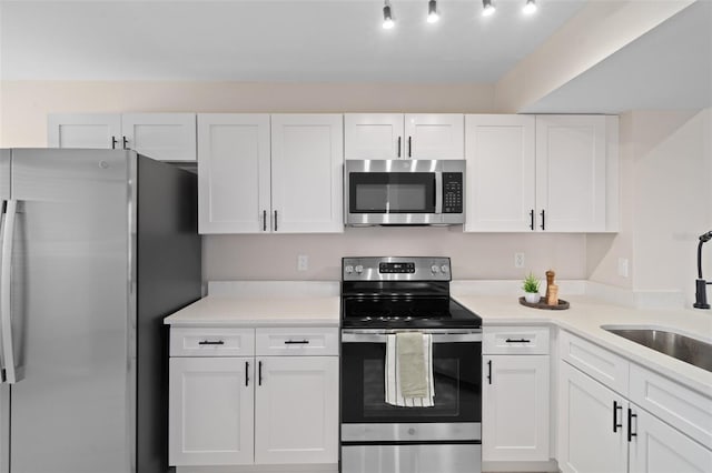 kitchen with stainless steel appliances, white cabinetry, and sink