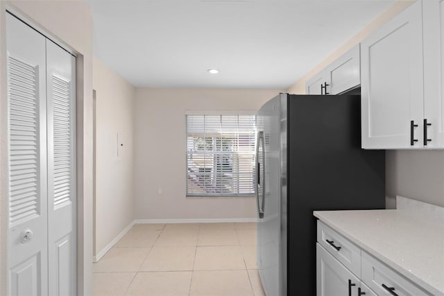 kitchen with stainless steel refrigerator, white cabinets, and light tile patterned flooring