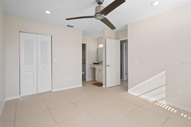 unfurnished bedroom featuring light tile patterned flooring, a closet, ceiling fan, and ensuite bathroom