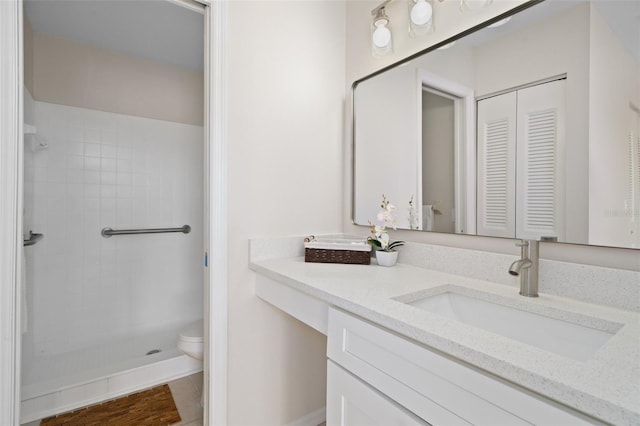 bathroom featuring toilet, vanity, wood-type flooring, and tiled shower