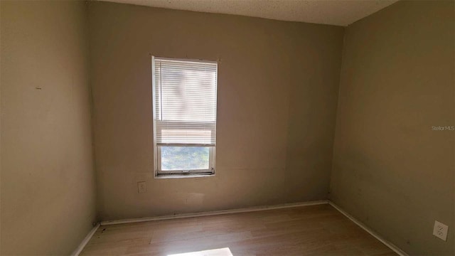 spare room with a textured ceiling and light hardwood / wood-style floors