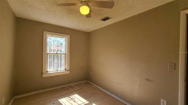 empty room featuring ceiling fan, hardwood / wood-style floors, and a textured ceiling