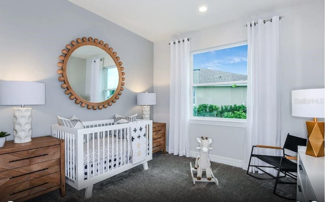 bedroom featuring dark colored carpet and a nursery area