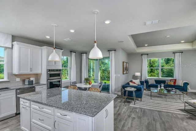 kitchen with white cabinets, pendant lighting, light wood-type flooring, and stainless steel appliances