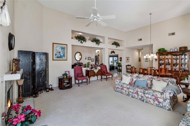 carpeted living room featuring ceiling fan with notable chandelier and a high ceiling