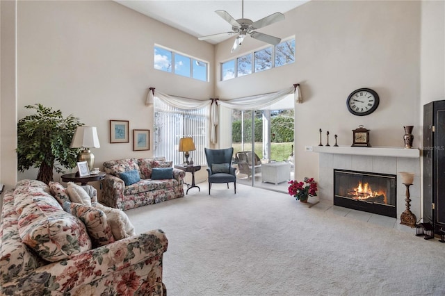 living room featuring carpet, ceiling fan, a towering ceiling, and a fireplace