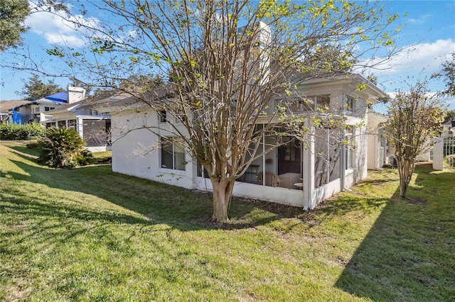 view of side of home featuring a sunroom and a yard