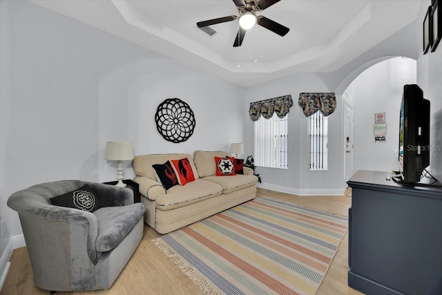 living room featuring a raised ceiling, ceiling fan, and hardwood / wood-style floors