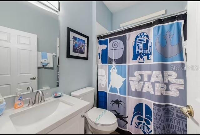 bathroom featuring vanity, toilet, and curtained shower