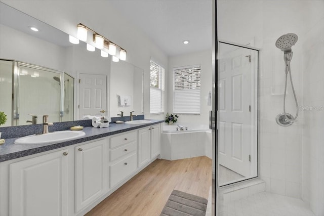 bathroom with hardwood / wood-style floors, vanity, and separate shower and tub