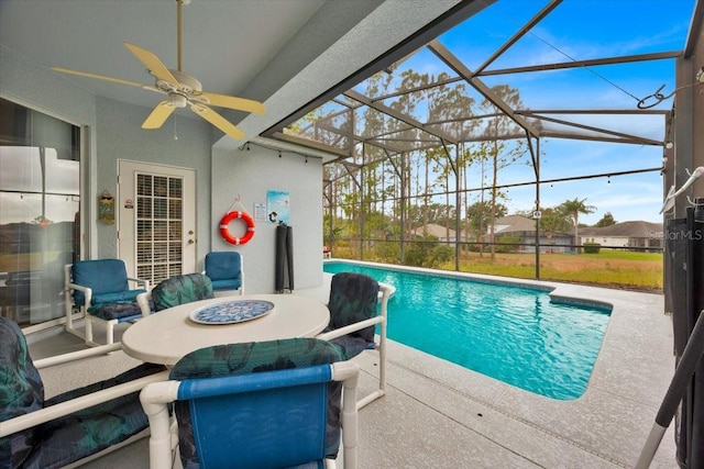 view of pool featuring a patio, glass enclosure, and ceiling fan