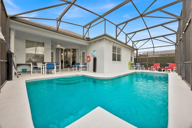 view of swimming pool featuring a patio, glass enclosure, and ceiling fan