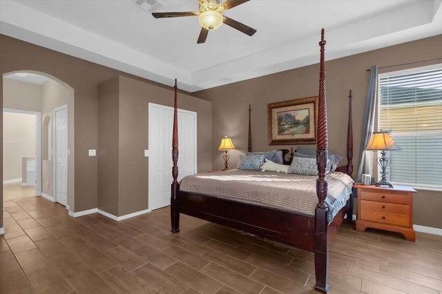 bedroom with a tray ceiling, ceiling fan, and wood-type flooring