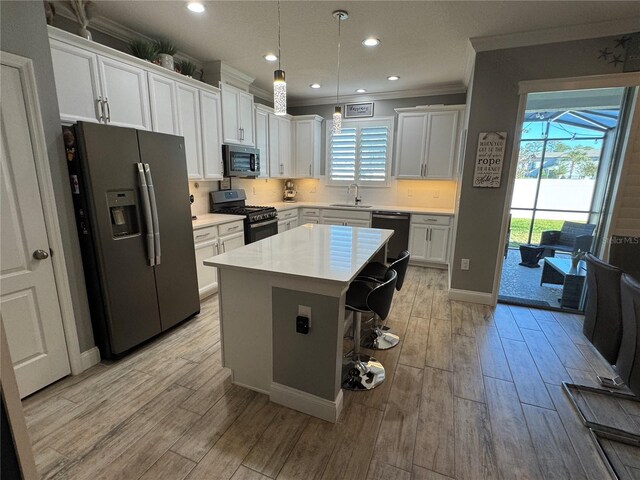 kitchen featuring appliances with stainless steel finishes, a breakfast bar, a kitchen island, sink, and white cabinetry