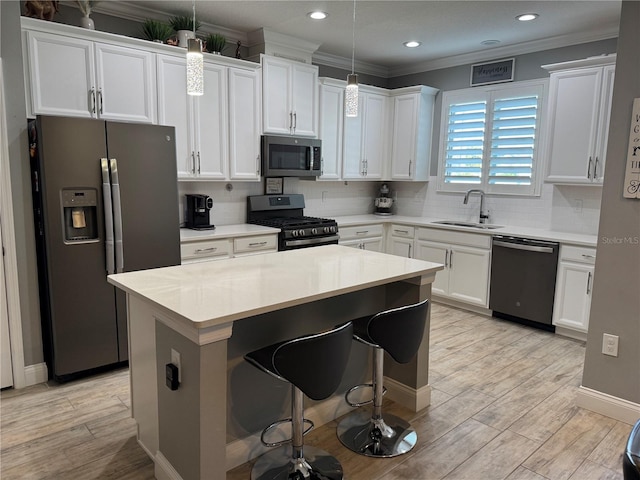 kitchen featuring decorative light fixtures, sink, white cabinetry, and stainless steel appliances