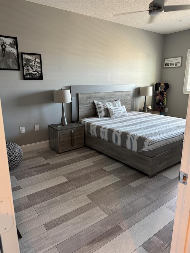 bedroom with ceiling fan, wood-type flooring, and a textured ceiling