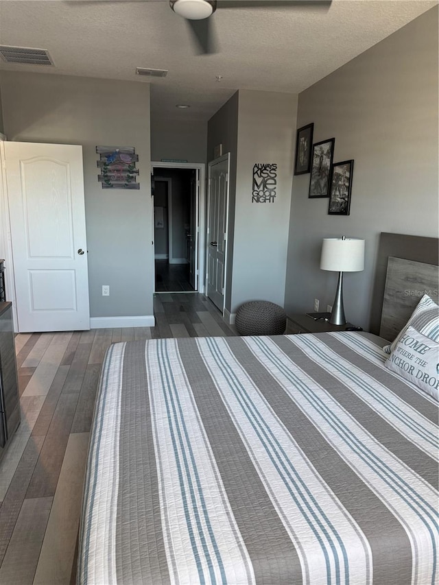 bedroom with dark hardwood / wood-style floors, ceiling fan, and a textured ceiling