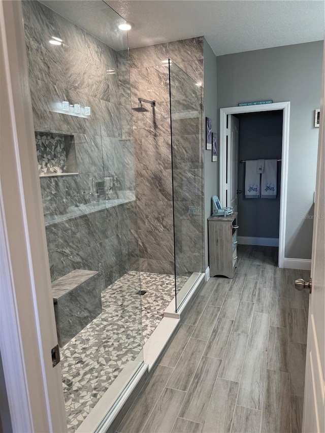 bathroom with a textured ceiling and tiled shower