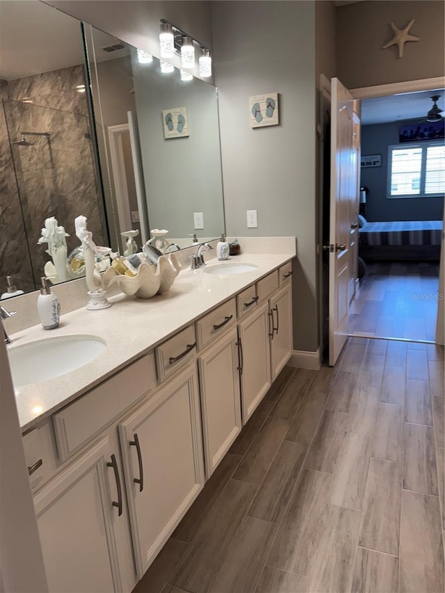 bathroom with tiled shower, wood-type flooring, and vanity