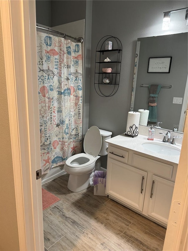 full bathroom with wood-type flooring, vanity, shower / tub combo, and toilet