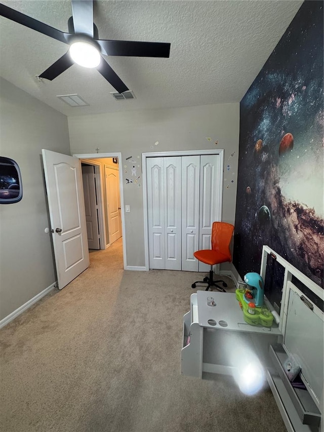 recreation room with light carpet, ceiling fan, and a textured ceiling