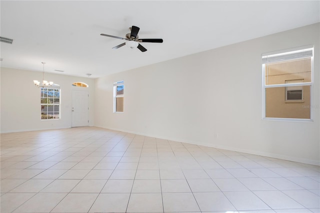 tiled empty room with ceiling fan with notable chandelier