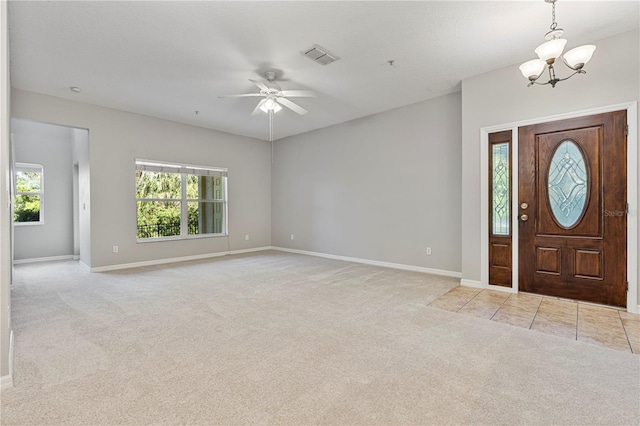 foyer featuring light colored carpet, a healthy amount of sunlight, and ceiling fan with notable chandelier