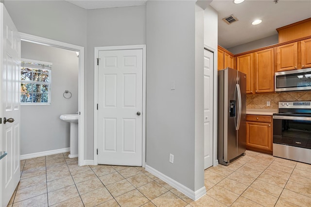 kitchen with light tile patterned flooring, appliances with stainless steel finishes, and tasteful backsplash