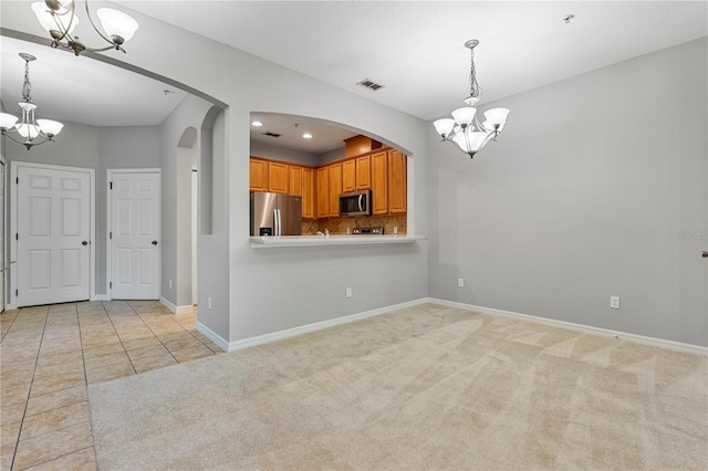 kitchen featuring decorative backsplash, light carpet, pendant lighting, and stainless steel appliances