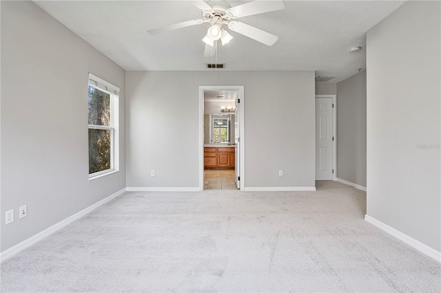 empty room featuring ceiling fan, light colored carpet, and a textured ceiling