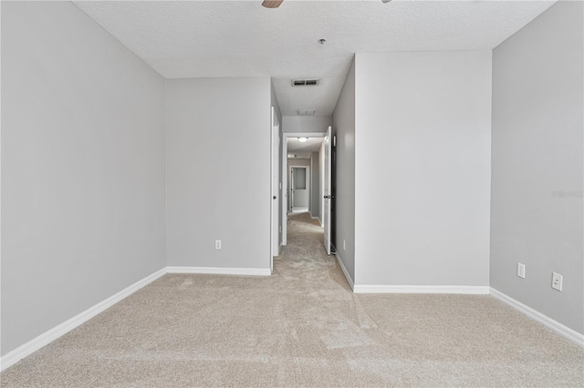 carpeted spare room featuring ceiling fan and a textured ceiling