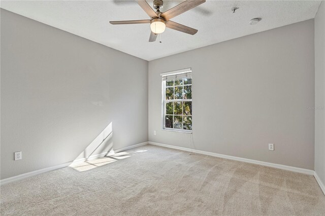 spare room featuring ceiling fan, light colored carpet, and a textured ceiling