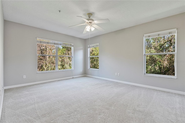 spare room with ceiling fan, a healthy amount of sunlight, and light carpet