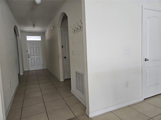 corridor featuring light tile patterned floors and a textured ceiling