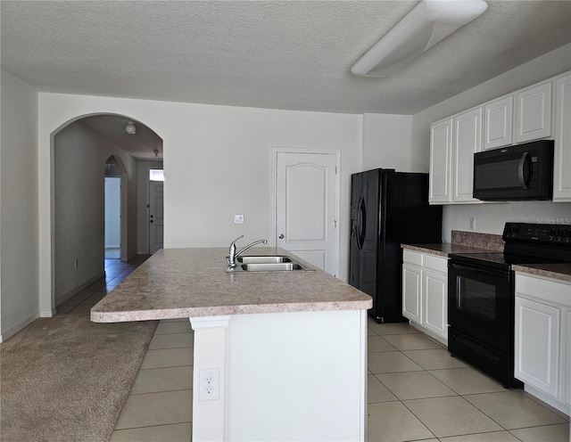 kitchen with light carpet, a kitchen island with sink, sink, black appliances, and white cabinets