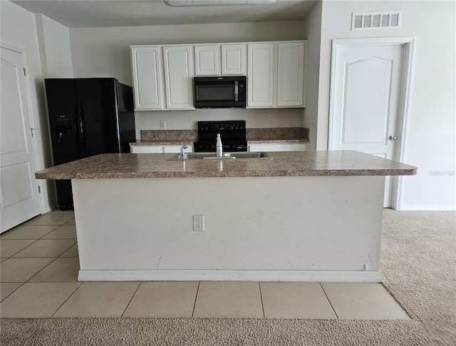 kitchen with sink, black appliances, light tile patterned floors, white cabinets, and an island with sink