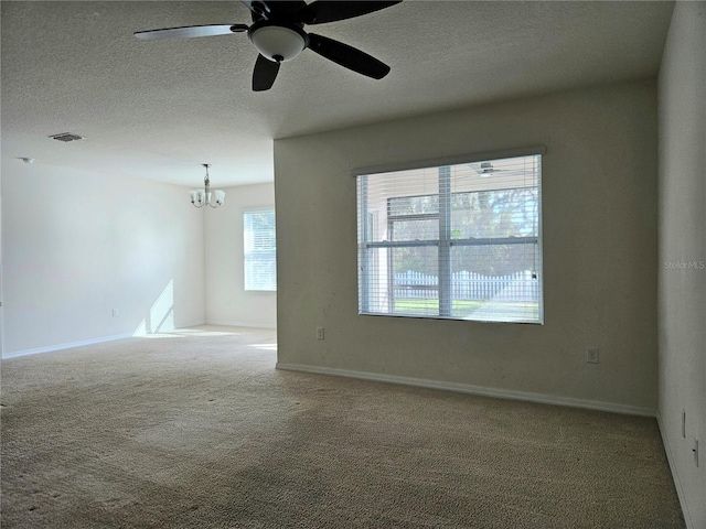 empty room with ceiling fan with notable chandelier, a textured ceiling, and carpet floors