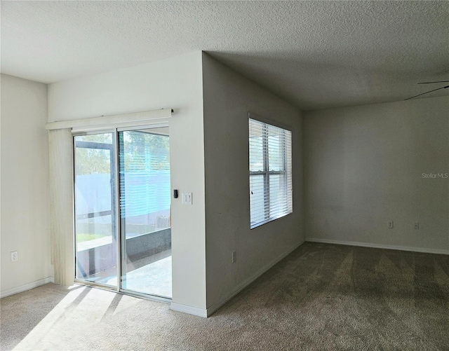 carpeted empty room featuring ceiling fan, a healthy amount of sunlight, and a textured ceiling